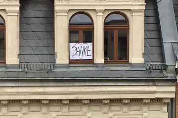 Ein Fenster, vor dem ein Schild mit der Aufschrift "Danke" und einem Herz hängt