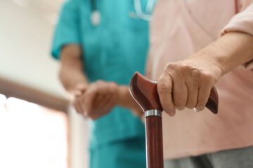 Nahaufnahme einer Hand, die auf einen Gehstock gestützt ist