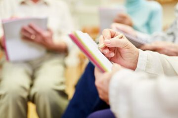 Detailaufnahme der Hände einer Seniorin beim Malen mit Buntstiften